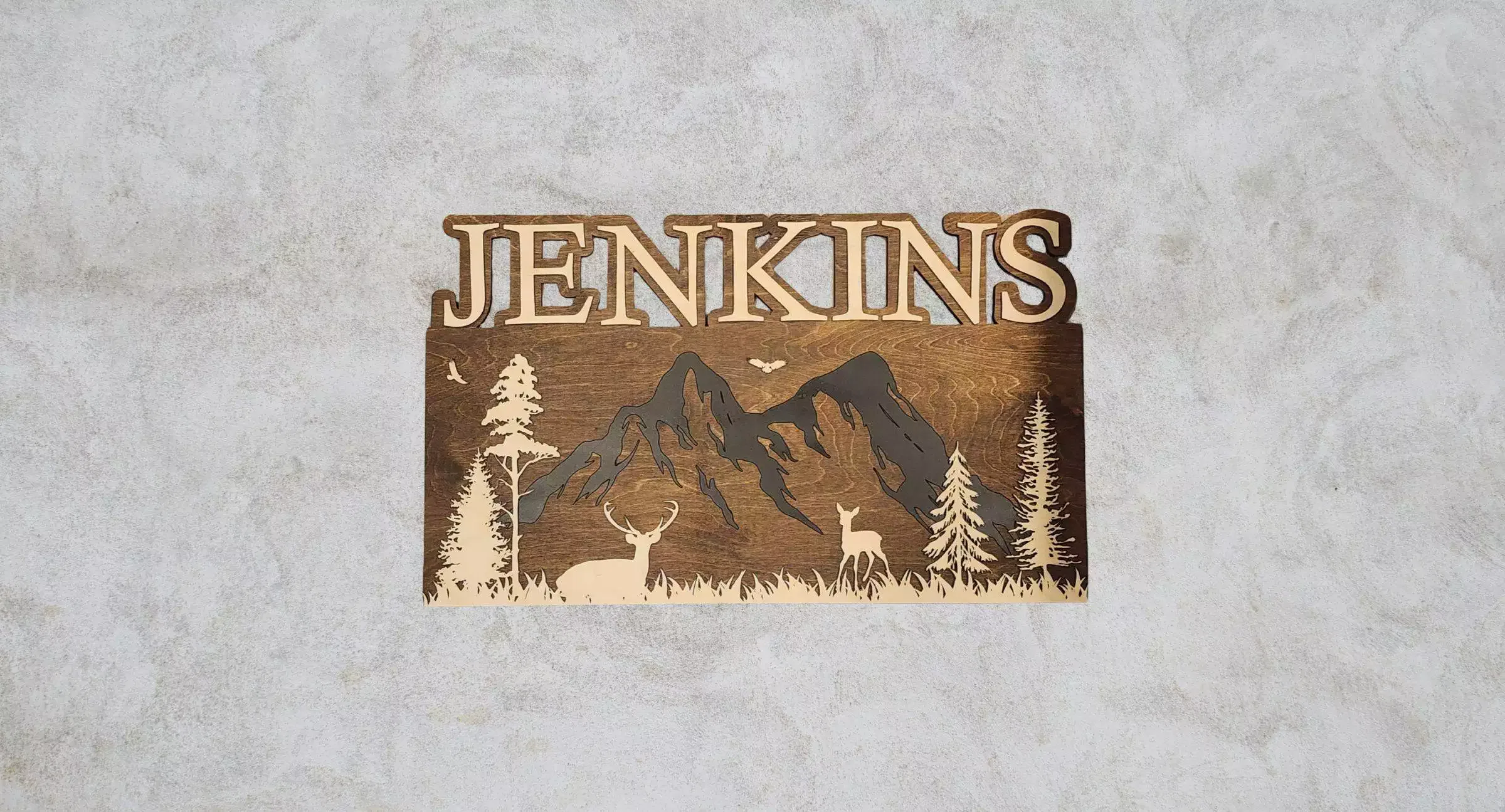 A rustic name sign featuring a forest scene